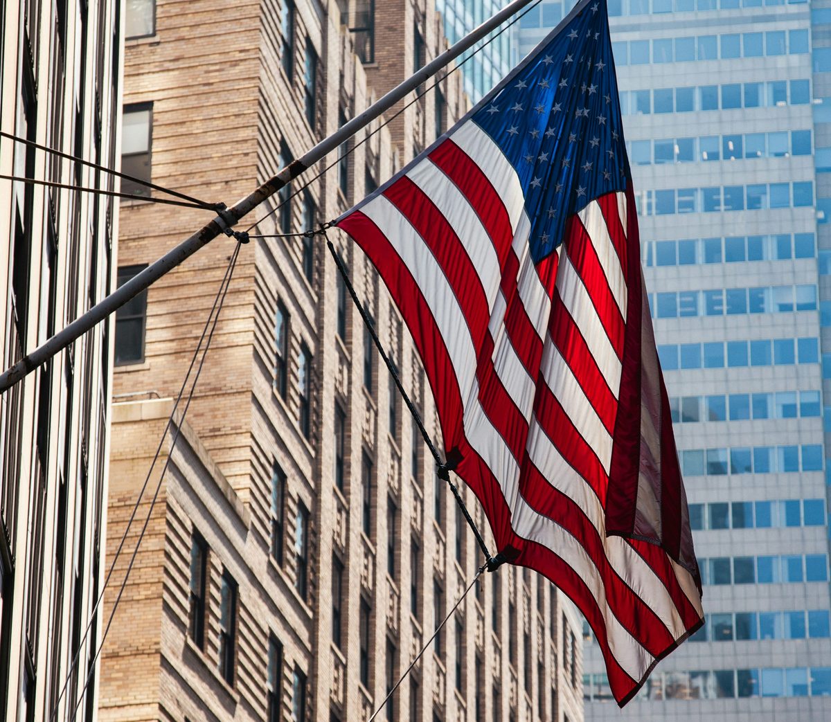 Una bandera de Estados Unidos ondeando entre rascacielos del distrito financiero de Nueva York.
